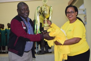 NSSF Vihiga Branch Manager Esther Kemei handing over the trophy to the Head Teacher  Gilwatsi Primary School. The School won in the English Verse category during the Kenya Music Festivals 2019.